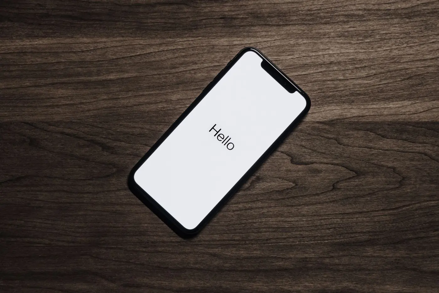 iPhone noir posé sur une table en bois affichant son écran de démarrage